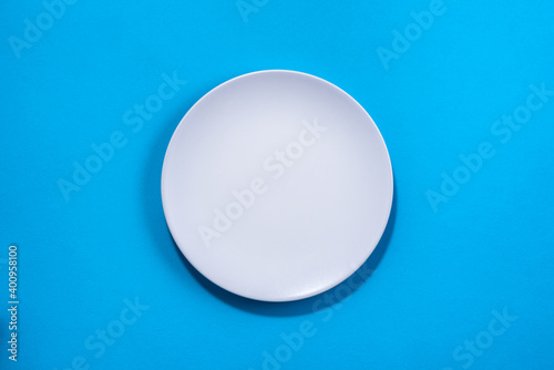 White plate on blue background. Selective focus. Shot from above