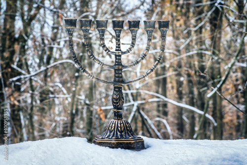 menorah stands in the snow against the background of nature photo