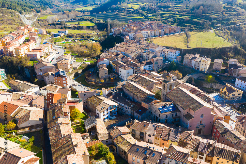 Scenic aerial view of small Spanish town of La Pobla de Lillet at foot of Pyrenees mountains on sunny fall day, Catalonia