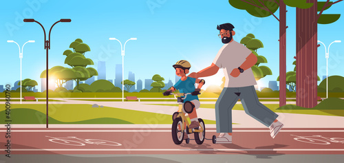 young father teaching little son to ride bike in urban park parenting fatherhood concept dad spending time with his kid cityscape background horizontal full length vector illustration
