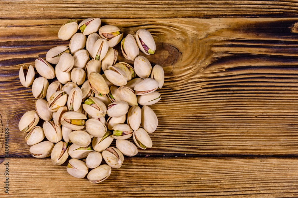 Pile of pistachio nuts on a wooden table Pile of pistachio nuts on a wooden table