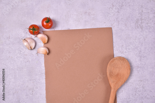 Red cherry tomato and garlic on brown paper for recipes with wooden spoon kitchen