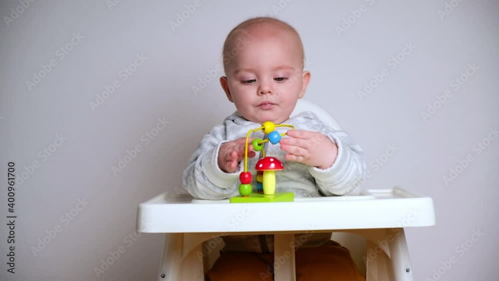 Infant baby boy playing with toys sitting in high chair. Infant baby boy playing with toys sitting in high chair.