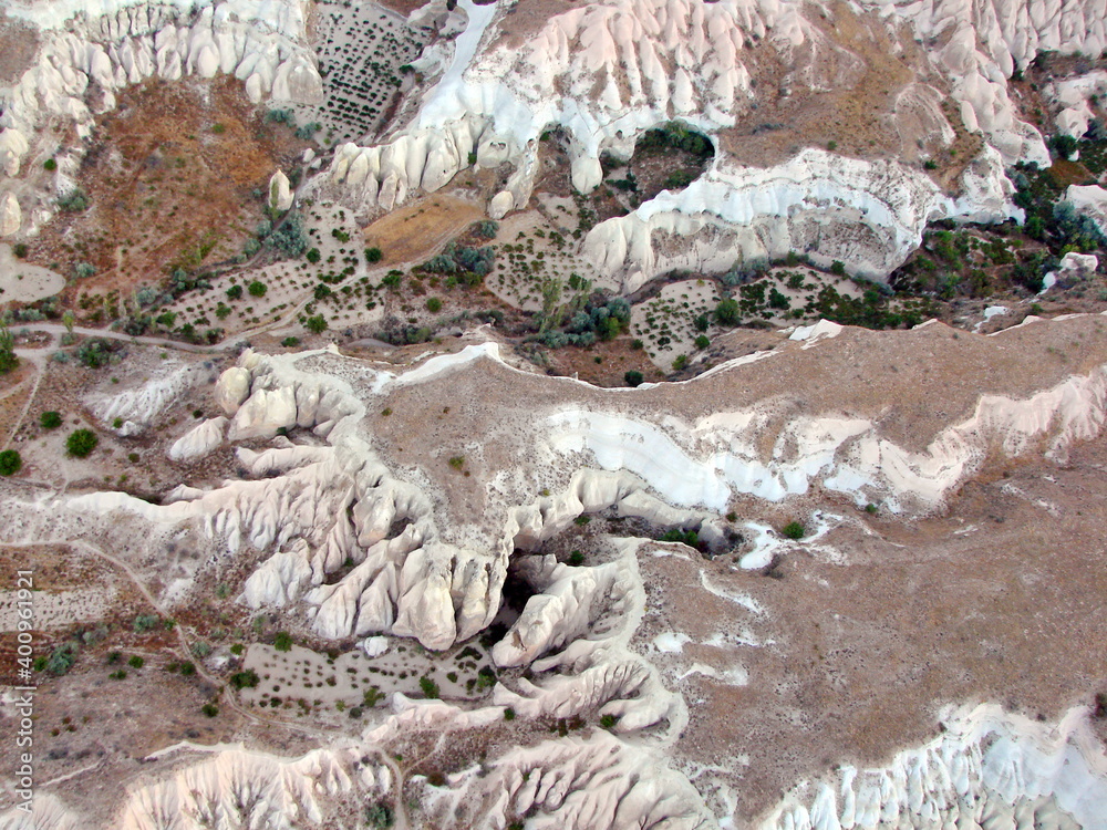 Fototapeta premium Panorama of the picturesque snow-white sharp-topped volcanic rocks of Cappadocia from the height of a balloon flight in dim light before sunrise.