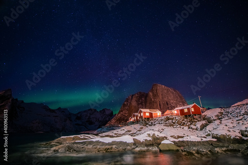 Aurora borealis on the Hamnoy village in Lofoten islands, Norway. Green northern lights above mountains. Night sky with polar lights. Night winter landscape.