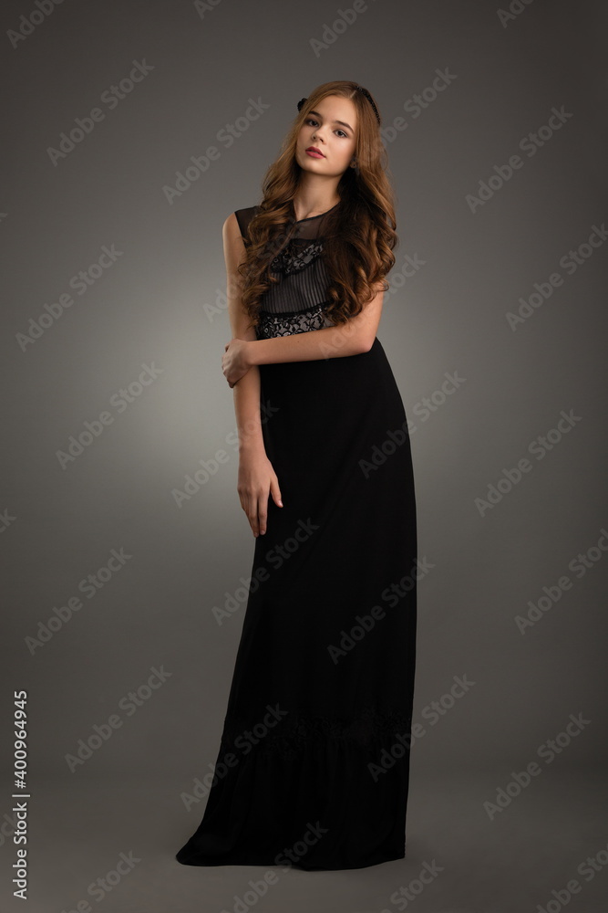 beautiful girl in a black dress posing in the studio on a gray background beautiful girl in a black dress posing in the studio on a gray background