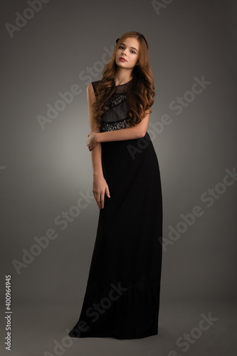 beautiful girl in a black dress posing in the studio on a gray background