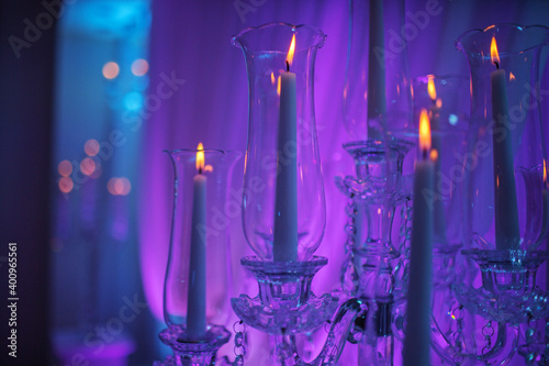 festive wedding table with burning candles and crystal in purple light. Crystal candle holder as a center piece at a wedding reception.