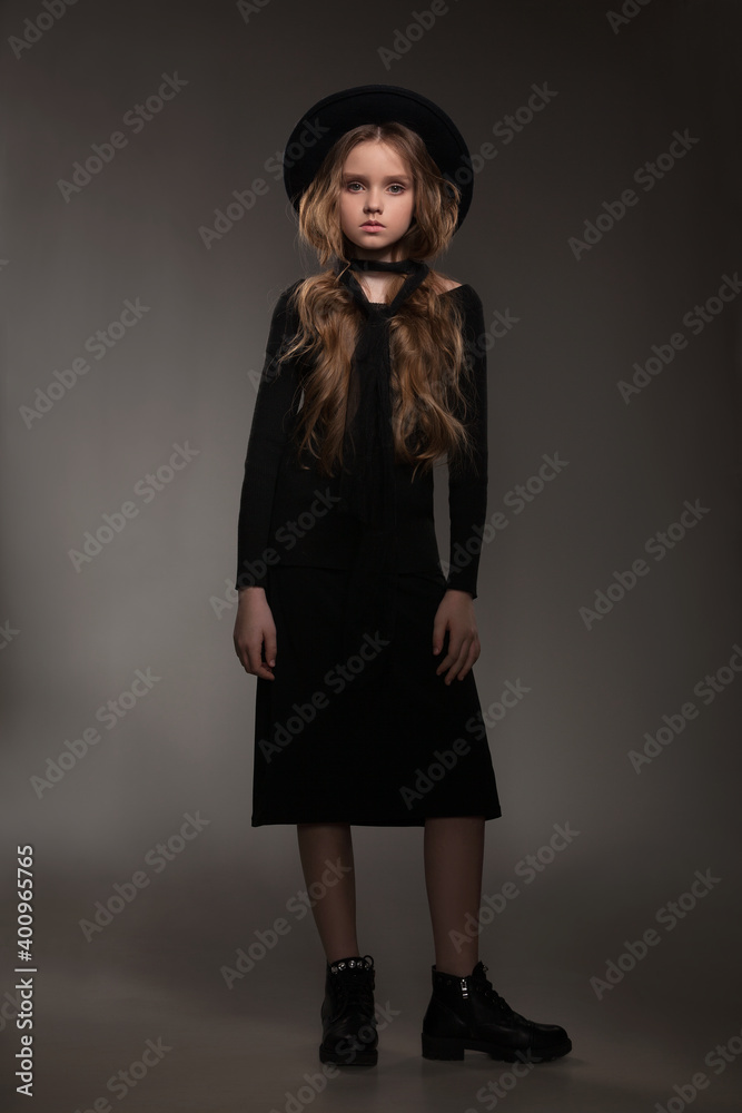 beautiful girl in a black dress and hat posing in the studio on a gray background beautiful girl in a black dress and hat posing in the studio on a gray background