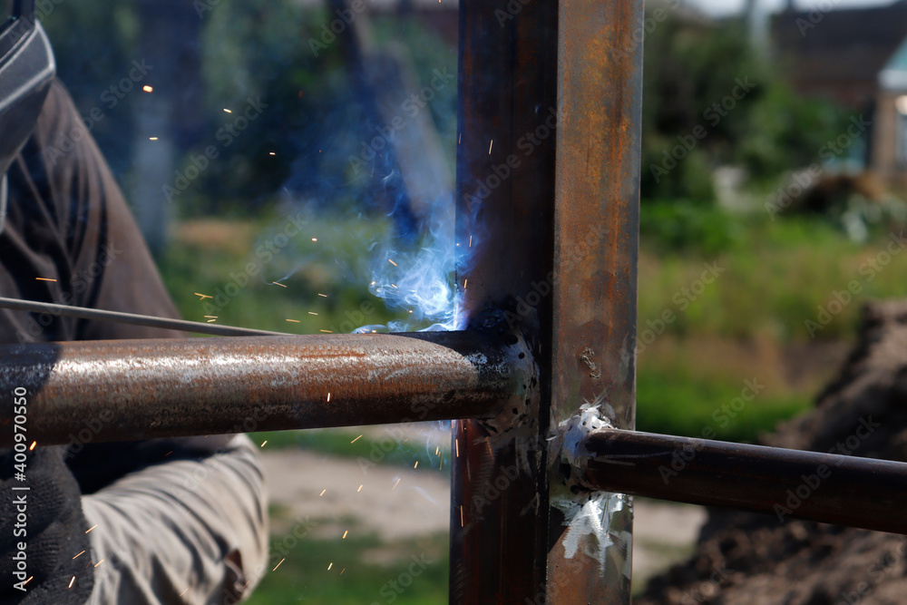 male welder welds iron parts at construction male welder welds iron parts at construction