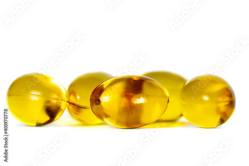 Yellow capsules of vitamin D, macro close-up of golden pills isolated on white