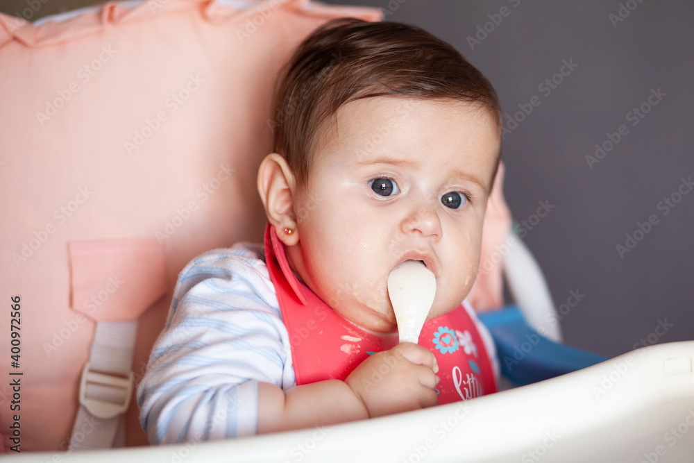 Baby is smeared with porridge, eats and looks into the camera. Baby is smeared with porridge, eats and looks into the camera.