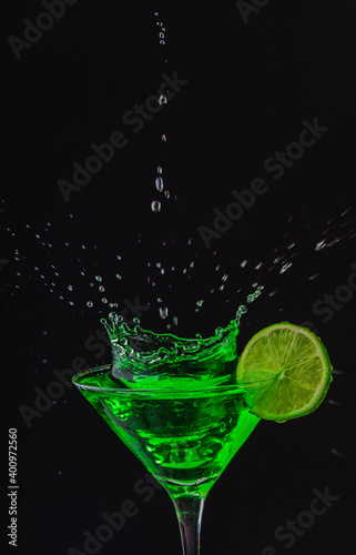 Green drink in a glass. Green water or limnad. A splash of green liquid similar to absinthe. Alcohol and alcoholism.