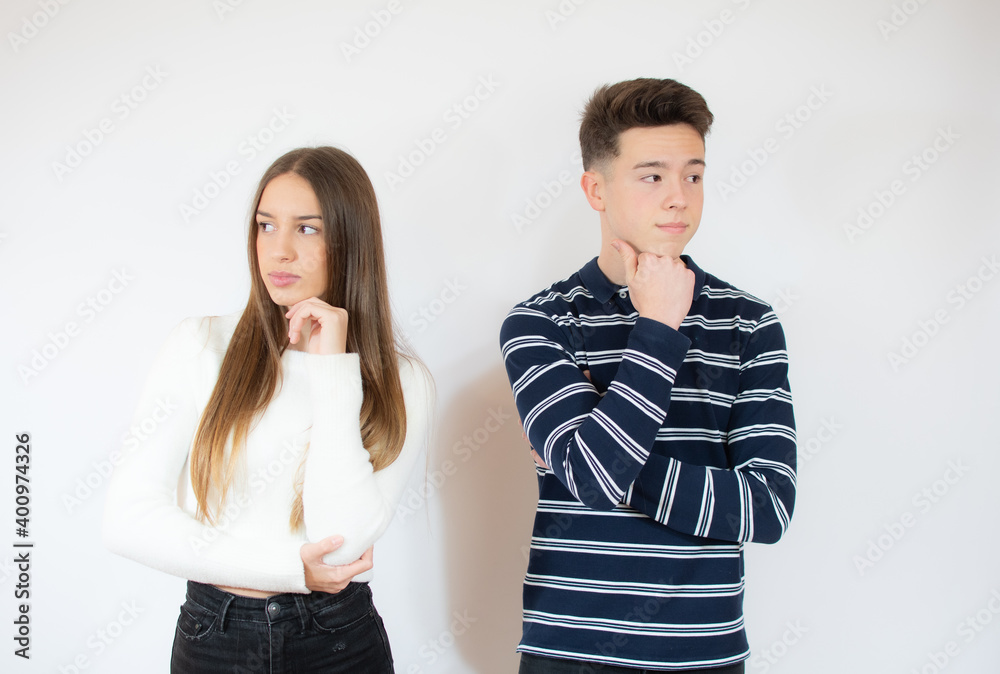 Disappointed young couple standing with arms folded over white wall Disappointed young couple standing with arms folded over white wall