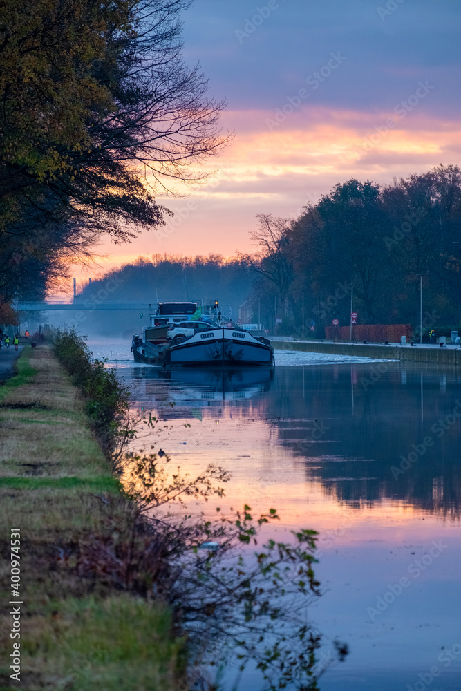 Fototapeta premium Cargo ship on a river during a misty sunrise morning. High quality photo