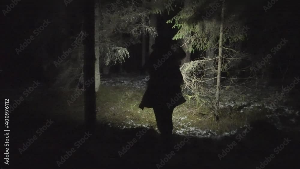 Young woman running through a deep deserted forest at night in winter. Camera follows. 4k footage.
