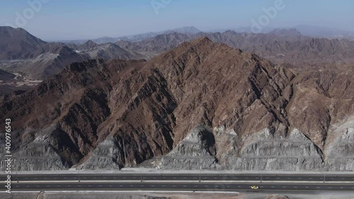 4k: Rear top view of UAE Mountain range, Traffic movement on new Khorfakkan road mountains in the background, Sharjah, United Arab Emirates. photo
