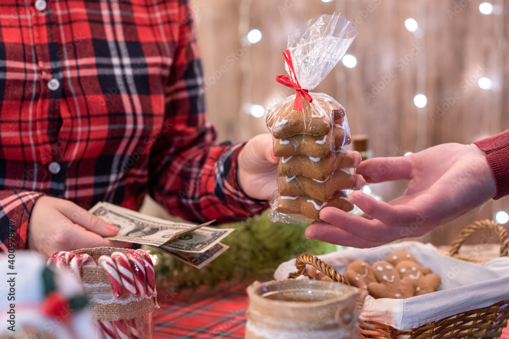 Man  customer buying christmas sweets at the bakery giving dollars to the woman seller