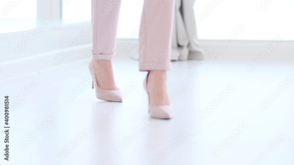 Fashionable woman wearing high heel shoes. Fashionable woman in high-heeled shoes. soft focus woman walking on white wooden floor. Fashionable woman wearing high heel shoes. Fashionable woman in high-heeled shoes. soft focus woman walking on white wooden floor.