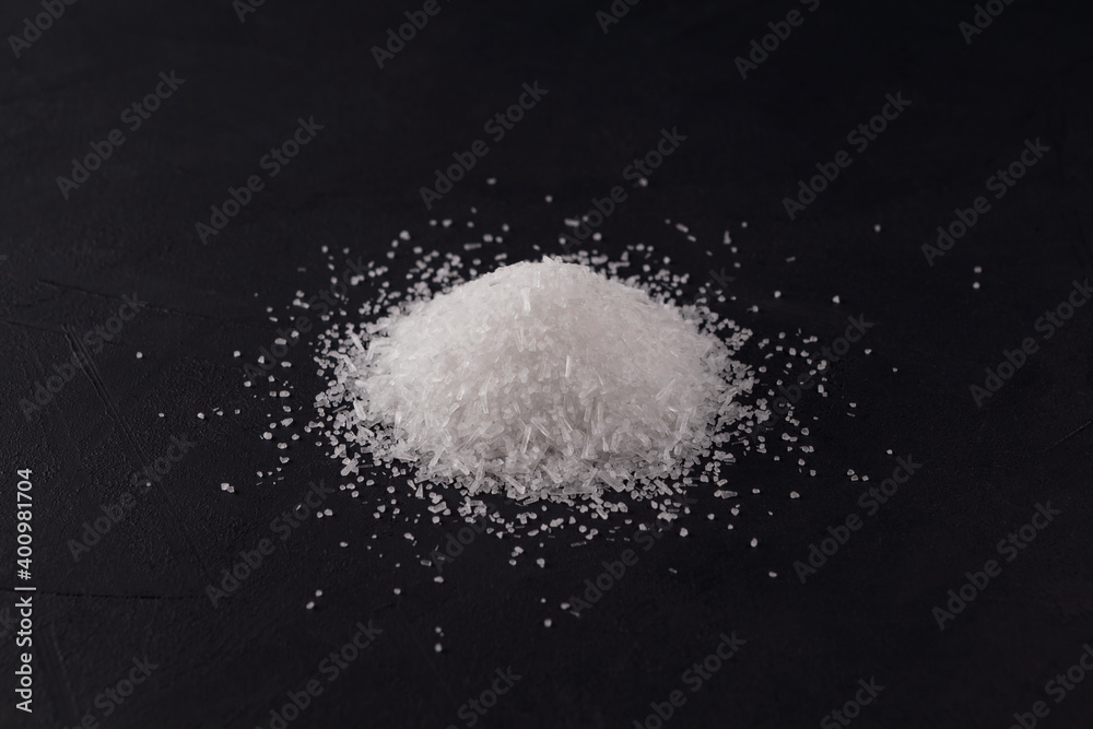 Glutamic acid monosodium salt on a dark background. Pile Msg or Food additive E621. Selective focus, copy space. Flavor seasoning for enhancing food impressions. The additive is used in food industry