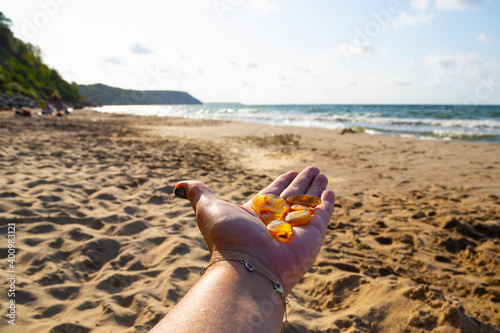 Amber in the palm of your hand. A group of pieces of transparent mineral Sunstone on a woman's hand against the background of the sea and sand. Semi-precious stones. photo