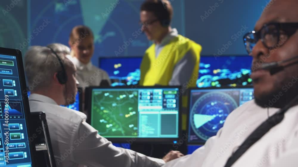 Workplace of the air traffic controllers in the control tower. Diverse team of aircraft control officers works using radar, computer navigation and digital maps. Aviation concept.