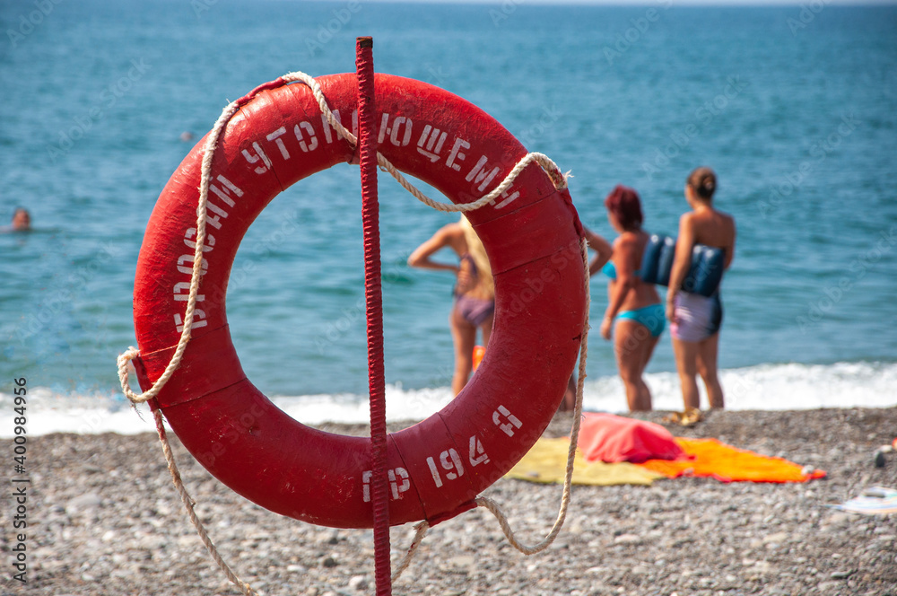 Scene lifebuoy on the beach and people looking towards the sea