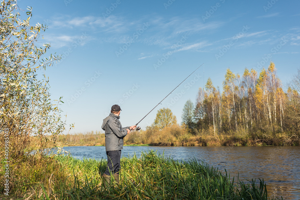 Man stands on the shore with a fishing rod. On a sunny day. Beautiful fishing landscape Man stands on the shore with a fishing rod. On a sunny day. Beautiful fishing landscape