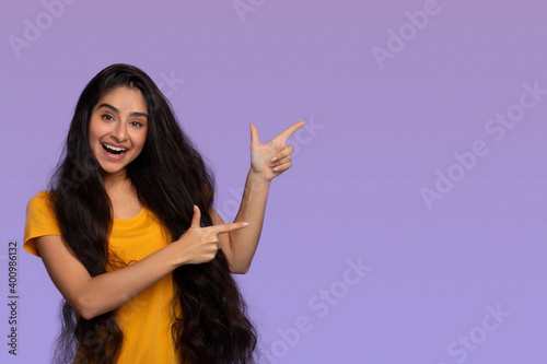 Excited indian lady pointing aside at copy space photo