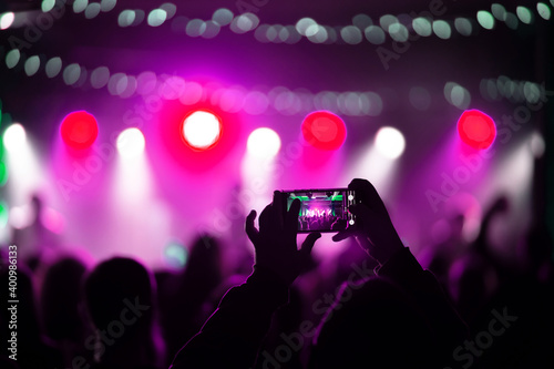 Person close up of recording video with smartphone during a concert.