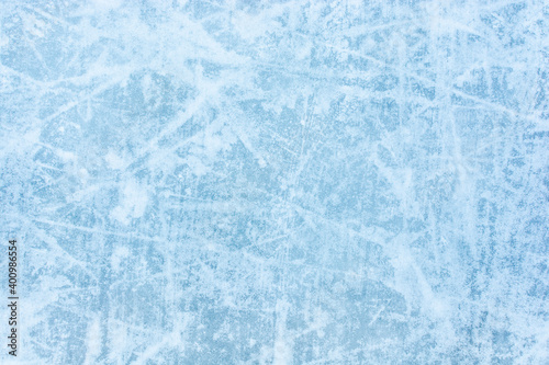 Ice blue background with skate tracks. Frozen water, sea. Frosty ice texture with scratches in winter. Skating rink.