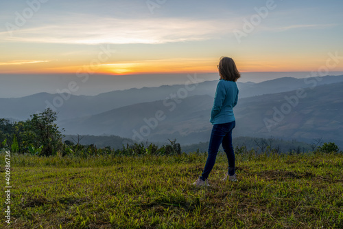 Young woman traveler looking at the sunrise over the mountain