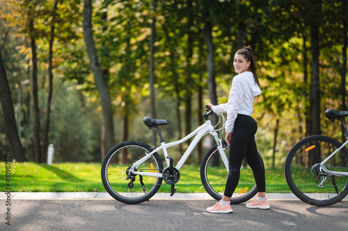 Fototapeta Naklejka Na Ścianę i Meble -  Beautiful girl posing at white bicycle. Walk in nature.