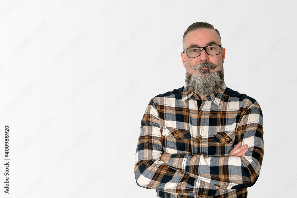 man with wide beard, glasses and plaid shirt, standing with crossed arms staring with serious face. concept people with different looks man with wide beard, glasses and plaid shirt, standing with crossed arms staring with serious face. concept people with different looks