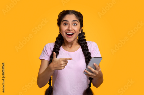 Excited indian woman using mobile phone, celebrating online win photo
