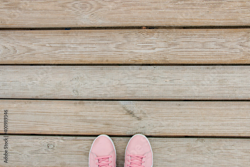 female feet in pink sneakers on a wooden pallet