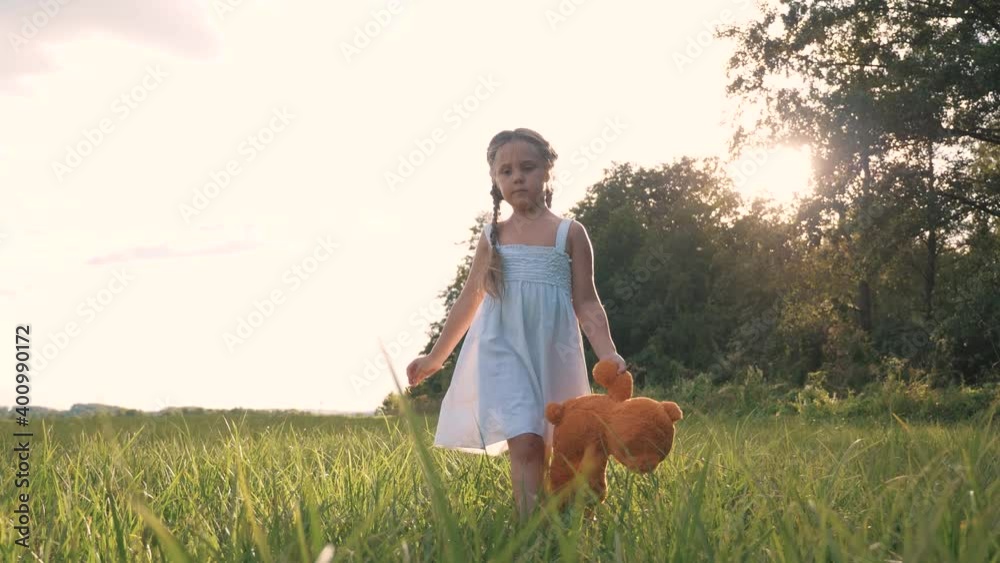 Little girl with a toy teddy bear in park. Cute girl with a teddy bear ...