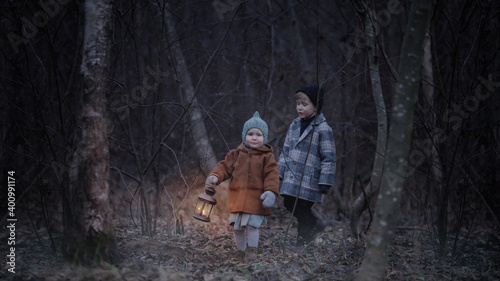 Fotografie Small children, walk through the night scary autumn or winter forest