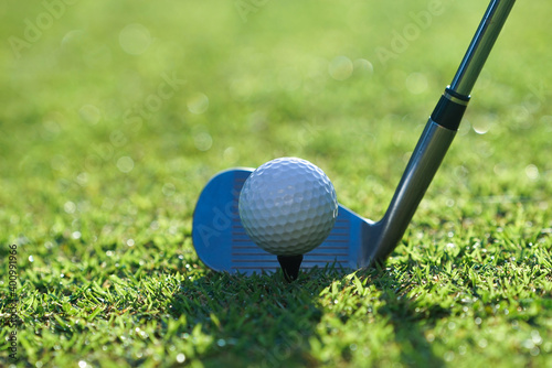 Golf clubs and golf balls on a green lawn in a beautiful golf course with morning sunshine.Close up of golf ball on a tee with the golf clubs ready to hit the ball.