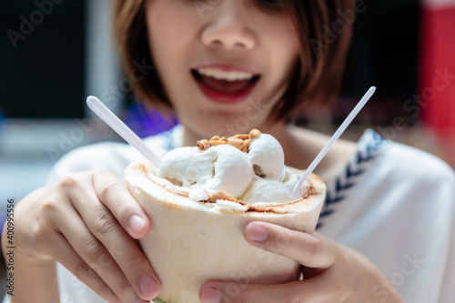 Coconut ice cream in coconut shell in woman hands enjoying eating  Thailand street food