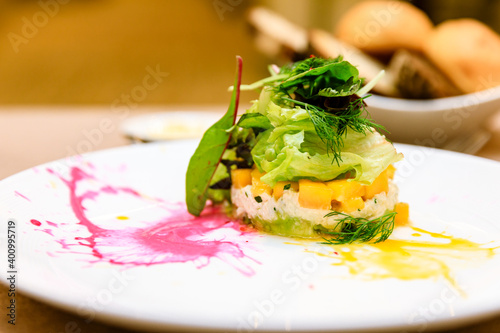 Crab Tian with mango and avocado, herb and vegetables salad with sauce on plate, starter or appetizer at a fine dining restaurant