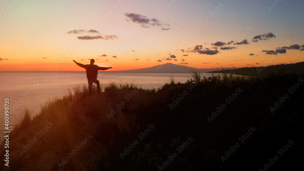 Silhouette di un ragazzo con le braccia in aria al tramonto 