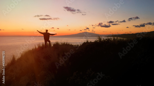 Silhouette di un ragazzo con le braccia in aria al tramonto 