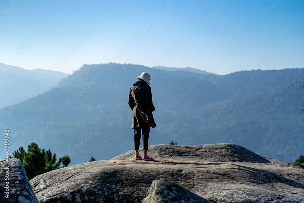 a woman stands alone on the peak of rock.