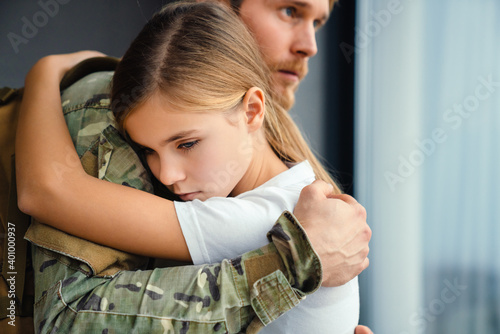 Konstfotografi Masculine sad military man hugging her upset daughter indoors