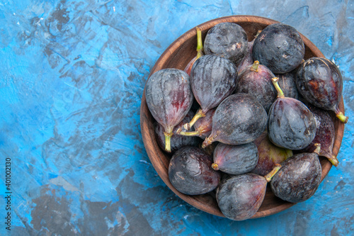 Close up view of black mission figs in a small brown pot on the right side on blue background photo