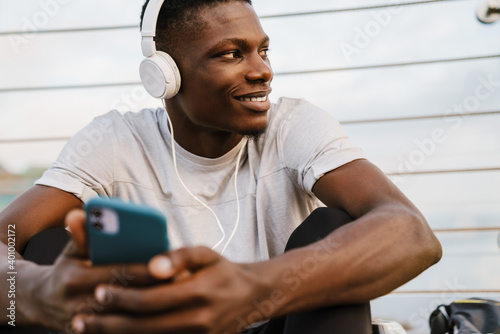 Relaxed smiling african sportsman sitting on the bridge