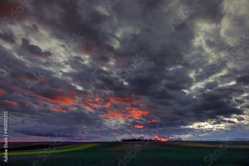 red dark clouds on the sky with green fields