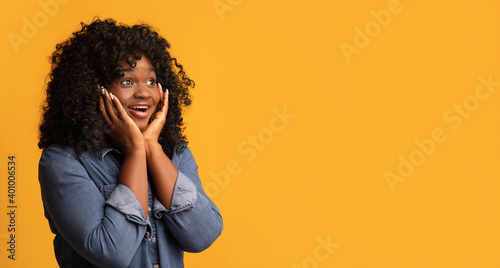 Amazed black woman looking at copy space for advertisement © Prostock-studio