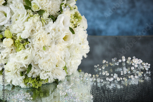 Wedding bouquet with white roses under the water drops on the mirror against grey and blue background. .  © VItaliy